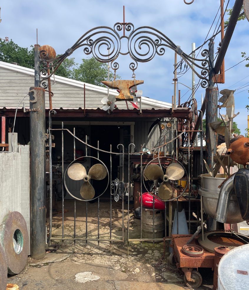 Wrought iron front gate with scrollwork and an anvil above it
